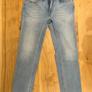 Jeans från Dressmann - Storlek: 32-32 Regular Fit Märke: Dressmann Skick: Mycket bra skick Färg: Ljusblå Användning: Perfekta för vardag och avslappnade tillfällen, dessa jeans ger en klassisk och bekväm look som enkelt kan matchas med olika stilar. 