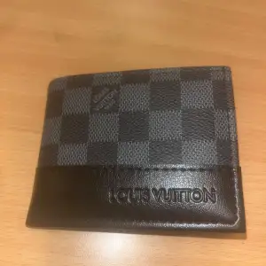 Säljer en snygg plånbok från Louis Vuitton i klassiskt rutigt mönster. Den är i svart och grått med en stilren design. Plånboken har flera fack för kort och ett myntfack med knapp. 500kr-mötas upp i malmö eller lund/550kr vid frakt eller kom med bud!