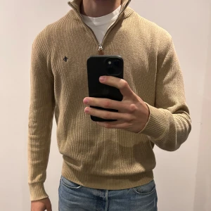 Beige Morris Bernard Half Zip, Storlek L - Morris pullover i väldigt bra skick. Inga defekter eller fläckar förutom att lappen inne i tröjan har släppt i ena änden (se bild #4). Tröjan är nytvättad och kommer från ett djur- och rökfritt hem.  Nypris: 1699 kr  Jag är 189 cm och väger 75 kg.