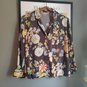 Levi's Floral blus, storlek M - Snygg blus med blommigt mönster i mörka färger. Blusen har en klassisk krage och knappar framtill. Sparsamt använd.