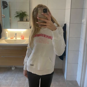 Vit fin hoodie med rosa text - En vit fin hoodie med rosa text från peak performance storlek s