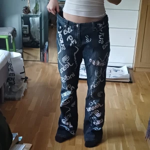 Jeans med tryck - Blå jeans, smått stretching, med vita tryck och broderingar, trycken börjar föagna, slitna vid hälen, annars bra kvalité. (Jag är 167cm) för stora i midjan för mig.