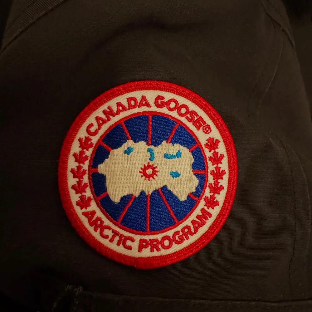 Säljer en svart figursydd parkajacka från Canada Goose med en mysig pälsfodrad huva. Jackan har långa ärmar och knappar framtill. Perfekt för kalla vinterdagar. Den är i bra skick och är i storlek S! . Jackor.