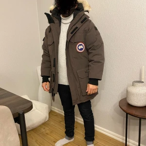 Brun parkajacka med pälsfodrad huva - Säljer en äkta mörkgrön/brun parka dun jacka från Canada Goose i storlek XXS UNISEX men passar en s-m vanlig storlek. Jackan har en pälsfodrad huva och flera praktiska fickor. Perfekt för kalla vinterdagar. Den är i väldigt fin skick och supervarm! 🧥🥶