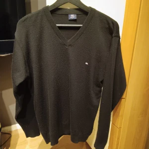 Svart och grå tröja från Tommy Hilfiger - Säljer två stilrena tröjor från Tommy Hilfiger. Den ena är en svart v-ringad tröja i storlek L, perfekt för höst och vinter. Den andra är en grå långärmad tröja i storlek 176, skön för vardagsbruk. Passar även S. Båda för 100