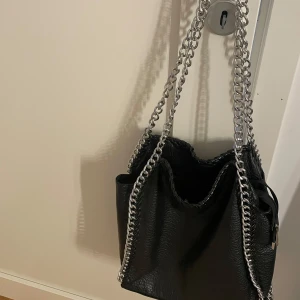 Svart väska - Säljer min tiamo väska i bra skick dock har det lossnat lite på baksidan som man kan se på sista bilden💕skriv för fler frågor 