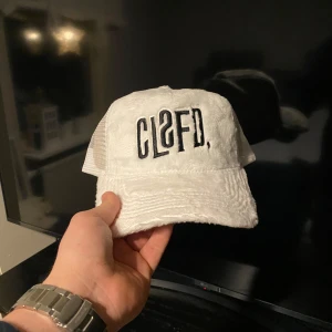 Vit keps från Classified - Snygg vit keps från Classified (sampeV2’s företag) med svart broderad text på framsidan. Kepsen har en mesh-design baktill för extra ventilation och en justerbar rem för perfekt passform. Perfekt för en avslappnad stil. Skön multi stil på kepsen som går att matcha med mycket, både för vardag, träning och kompis häng. Helt ny och oanvänd för jag köpte en annan som jag tyckte passade bättre på mig. (Original pris 549kr)