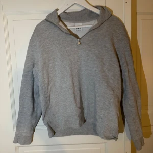 Grå hoodie från Zara - Säljer en stilren grå hoodie från Zara med dragkedja vid halsen. Perfekt för en avslappnad look. Tröjan har långa ärmar och är tillverkad i mjukt material för extra komfort.