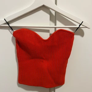 Röd ribbad tubtopp - Snygg röd ribbad tubtopp perfekt för sommaren. Den har en hjärtformad urringning och är tillverkad i ett stretchigt material som ger en bekväm passform.