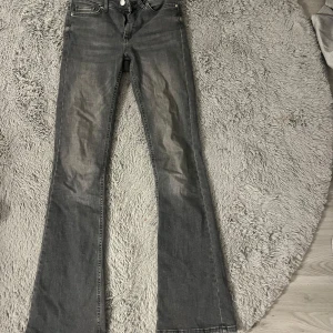 Grå bootcut jeans från ONLY - Snygga grå bootcut jeans från ONLY med klassisk femficksdesign. Perfekta för en avslappnad stil med en touch av retro. Tillverkade i slitstarkt denim för en bekväm passform. Lite slitage vid fötterna men inte mycket. Medelhög-låg midja.