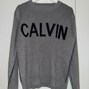Calvin Klein Sweatshirt - Snygg grå tröja från Calvin Klein med svart text på framsidan. Tröjan har långa ärmar och en klassisk rund halsring. Väldigt bra skick. Vid frågor är det bara att skriva. 