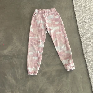 Rosa camo mjukisbyxor från Lindex - Säljer ett par bekväma rosa camo mjukisbyxor från Lindex. Byxorna har elastisk midja och muddar vid bensluten för extra komfort. Perfekta för en avslappnad dag hemma eller ute. Dem har små för kar på ena fram benet, vi har inte fått bort dem i tvätten❄️