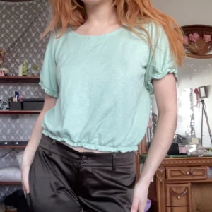 Mintgrön topp med rysch - Säljer en mintgrön/småglittrig topp från Pretty-Jo med ryschade ärmar och nederkant i tjock bomull.  Längd: 52cm Bredd: 43cm Ärm: 21cm