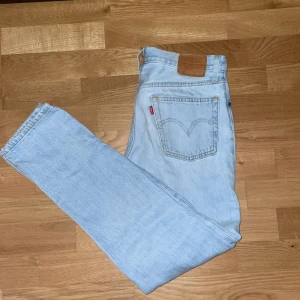 Ljusblå jeansbyxor från Levis - Säljer ett par klassiska ljusblå Levis jeans med knappgylf och femficksdesign. Perfekta för en avslappnad stil. De har en straight passform och är tillverkade i slitstarkt denim. Sitter perfekt, inge baggy alls!