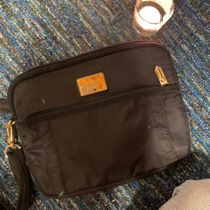 Svart väska från Victoria's Secret - Snygg svart väska från Victoria's Secret med leopardmönstrat foder. Väskan har en dragkedja och en praktisk framficka med gulddetaljer. Perfekt för att bära med stil.