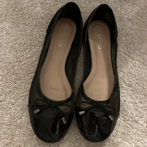 Svarta ballerinaskor - Eleganta svarta ballerinaskor med glansig tå och prickigt meshmaterial. Skorna har en dekorativ rosett framtill och är perfekta för en stilren look, perfekt till alla sorts aktiviteter där man vill känna sig extra fin☺️Använda 2 gånger, säljer pga för stora. 