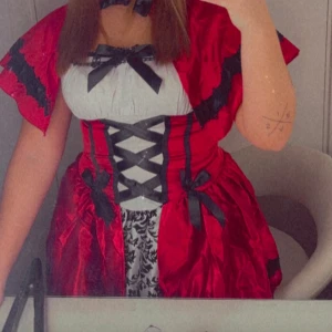  rödluvan klänning köpt från party kungen - Säljer en röd rödluvan klänning från party kungen. Klänningen har svarta snörningsdetaljer och spets, med en matchande cape. Perfekt för en unik och iögonfallande look till halloween. Kostade 700 nypris. Endast använd vid 1 tillfälle 