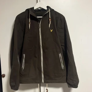 Jacka från Lyle & Scott stl M - Säljer en denna mörk gröna jacka från Lyle & Scott med dragkedja och huva. Jackan är i mycket bra skick. Och är ej använd särskilt mycket. Jag är 191 cm (OBS sitter lite kort på mig) vid fråga är det bara och skriva. 