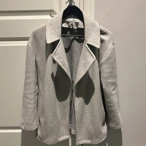 Grå kappa från Zara - Snygg grå kappa från Zara i storlek S med klassisk krage och långärmad design. Perfekt för kyligare dagar och ger en stilren look. Passar bra till både vardag och mer uppklädda tillfällen. Skön passform och mjukt material. Begagnad köpt
