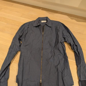 Blå skjorta med dragkedja från John Henric - Marinblå overshirt med dragkedja från John Henric. Dubbel dragkedja så den kan öppnas nedifrån också. Storlek 39 vilket motsvarar medium.