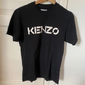Svart t-shirt från Kenzo - Snygg svart t-shirt från Kenzo med vit logga på bröstet. Perfekt för en stilren look.