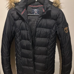 Vinterjacka Vinson Polo club  - Jacka i fint skick. Syntetfodrad. Svart med luva, fuskpälsen på luvan  är avtagbar. Stl 160/ XS. 