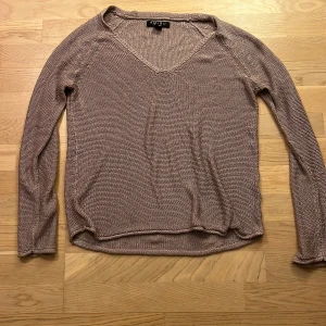 Lila stickad tröja från Amisu - Säljer en stilren lila stickad tröja från Amisu. Tröjan har en v-ringad design är ganska tunn och har långa ärmar. Passar bra till både jeans och kjol.