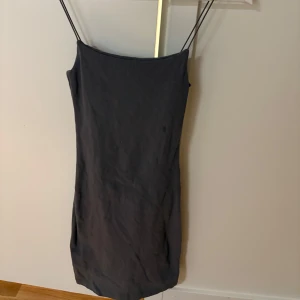 Svart klänning från Zara - Snygg grå klänning från Zara med smala axelband. Perfekt för en stilren look. Klänningen har en enkel och elegant design som passar till många tillfällen. Liten fläck på bröstet som går att ta bort med fläckborttagning 