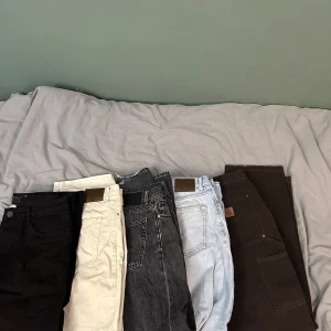 Jeans - Säljer fem par byxor i olika färger: svart, beige, mörkgrå, ljusblå och bruna. Perfekta för att variera din stil. Byxorna har klassisk design med fickor och bälteshällor. Kom privat om något par intresserar er😊