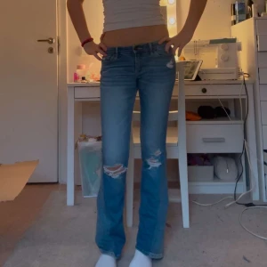 Blå bootcut jeans med slitningar - Jätte snygga Hollister jeans med snygga håll. Dom har rosa detaljer på sömmarna och på fickorna. Sitter lite kort i längden på mig som är 173. Skulle passa bättre på någon som är 163-172. Jag har sytt ut som till bootcut, men med ett tyg som är väldigt likt. Dom är noggrant utsydda. Innerbenslängd 79. Midjemått 37 men väldigt stretchiga💕 skriv vid interesse💕
