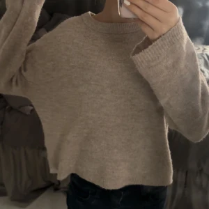 Beige stickad tröja - Mysig beige stickad tröja med långärmad design och croppad passform. Perfekt för kyligare dagar och ger en avslappnad look.