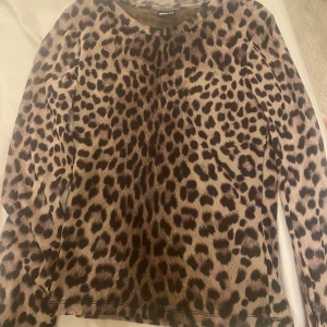 Leopardmönstrad långärmad tröja från H&M - Snygg leopardmönstrad tröja från H&M med långa ärmar. Perfekt för att ge din outfit en djärv touch. Tröjan är i en mjuk och bekväm kvalitet.