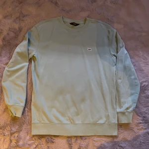 Ljusgrön sweatshirt från Lee - Säljer en stilren ljusgrön sweatshirt från Lee. Tröjan har en rund halsringning och långa ärmar med ribbade muddar. Perfekt för en avslappnad look.