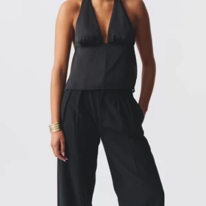 Svart halterneck topp - Snygg svart halterneck topp med djup urringning och knytning i ryggen. Perfekt för en kväll ute eller festliga tillfällen. Toppen har en elegant och stilren design. Nypris 360kr. Använd endast en gång så inga defekter alls, som ny. Pris går att diskuteras💗