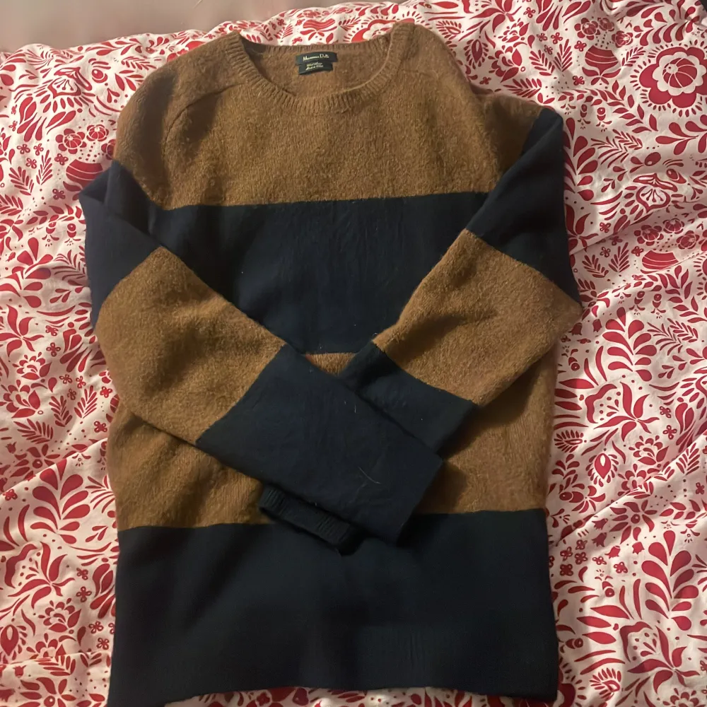 Snygg tröja från Massimo Dutti i brunt och marinblått. Den har ett randigt mönster och är tillverkad i ullblandning. Perfekt för kyligare dagar med sin långärmade design.. Neuletakit & Villapaidat.