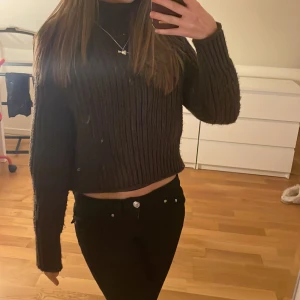 Brun stickad polotröja - Säljer en mysig brun stickad polotröja med ribbade detaljer. Tröjan har långa ärmar och är croppad