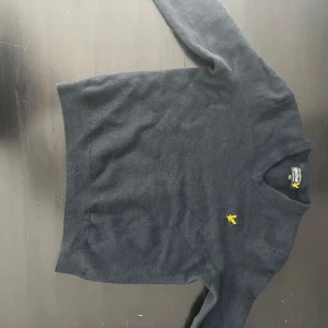 Mörkblå tröja från Lyle & Scott - Snygg mörkblå tröja från Lyle & Scott med deras ikoniska gula logga på bröstet. Tröjan har en klassisk design med långa ärmar och rund hals. Perfekt för en stilren look. Tröjan har 3/4 armar och passar xxs-s.          PRIS GÅR ATT DISKUTERA