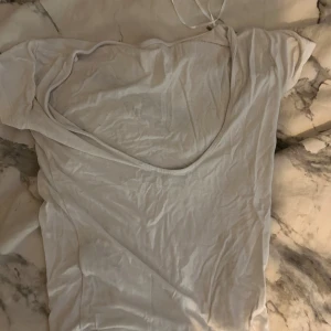 Vit kortärmad topp - Säljer en enkel vit kortärmad topp med öppen rygg. Perfekt för en avslappnad stil. Passar bra till jeans eller kjol.