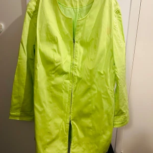 Neongul kavaj  med dragkedja - Snygg neongul kavaj  med dragkedja framtill. Perfekt för att sticka ut i mängden. Jackan har långa ärmar och en enkel design utan krage.