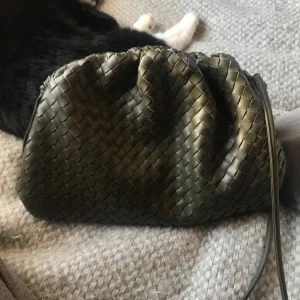 Flätad clutch i armégrön från Jackie Stockholm - Snygg och stilren flätad clutch i en armégrön nyans från Jackie Stockholm. Väskan har en unik flätad design och är perfekt för att bära det viktigaste. Den har en praktisk öppning och en elegant look. 💓🌟 Köpt här på Plick så tyvärr inget äkthetsvevis. Väskan är mycket sparsamt använd så ser ut precis som ny! Nypris 2800kr                                                                32x22 cm