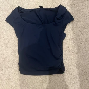 Mörkblå topp - Snygg mörkblå topp med korta ärmar och en rundad halsringning. Perfekt för en stilren look. Materialet är mjukt och stretchigt för en bekväm passform.