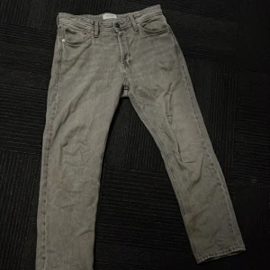 Grå jeans från Jack & Jones - Snygga grå jeans från Jack & Jones med klassisk femficksdesign och knappgylf. Perfekta för en avslappnad stil. Köpte för inte alls längesedan för 600 så fint skick W30 L30