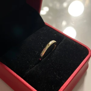 Guldfärgad ring med stenar - Elegant guldfärgad ring prydd med små färgade stenar i rött, blått och gult. Perfekt för att ge en färgglad touch till din stil. 