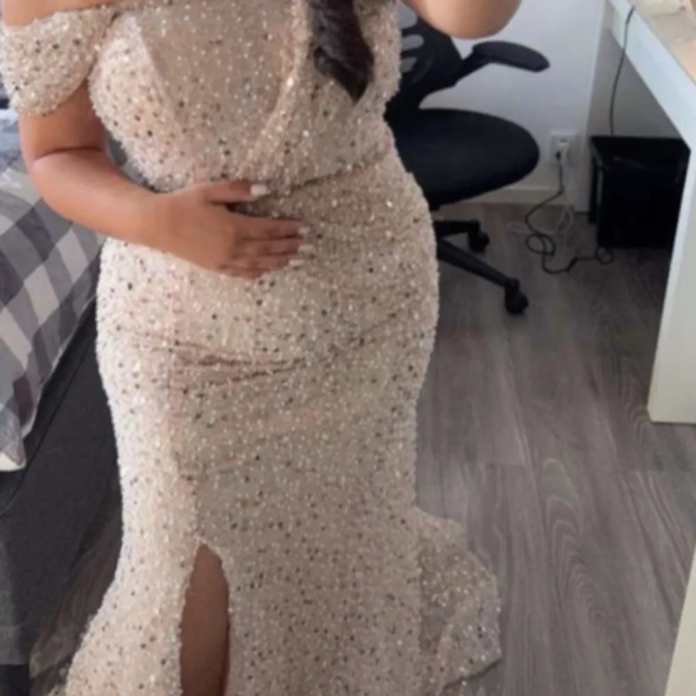 Säljer en elegant champagnefärgad klänning med glittrande paljetter. Klänningen är axelbandslös och har en lång design med en slits framtill. Perfekt för en glamorös kväll!. Mekot.