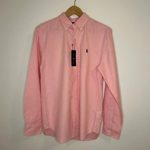 Rosa skjorta från Ralph Lauren - Snygg rosa skjorta från Ralph Lauren. Stor i storleken men en size S. Nytt skick. Skicka vid frågor kring skjortan!! 🗣️🗣️🚨