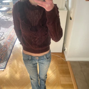 Vinröd stickad tröja med volangdetaljer - Säljer en vinröd stickad tröja från Zara med vackra volangdetaljer runt halsen. Tröjan har ett fint mönster och långa ärmar. Säljs inte längre!