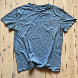 Ralph Lauren Blå t-shirt  - Säljer en blå t-shirt från Polo Ralph Lauren i storlek L. T-shirten är tillverkad i 100% bomull och har en liten röd broderad logotyp på bröstet. Perfekt för en avslappnad stil.