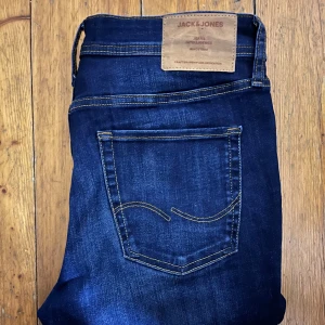 Mörkblå jeans från Jack & Jones - Snygga mörkblå jeans från Jack & jones. De har en knappgylf och är tillverkade i ett slitstarkt denimtyg. Pris kan diskuteras