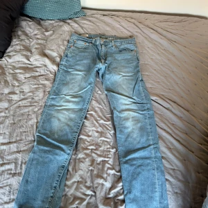 Blå jeans från Levi's - Säljer ett par klassiska blå jeans från Levi's. De har en straight passform och är tillverkade i denim med en traditionell femficksdesign. Perfekta för en avslappnad stil.