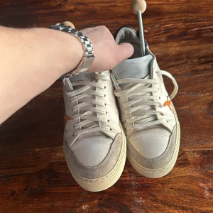 Vita sneakers med broderade fåglar - Snygga vita sneakers från Axel Arigato med broderade fåglar i olika färger på sidan.          Storlek 40.  Nypris 2400  skick 8/10.  Kommer med box